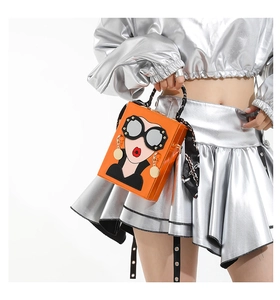 Detail of orange box bag with pop art lady face, silk handle and metal clasp accents