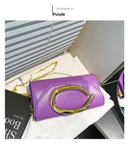 Detail shot of purple leather clutch bag featuring iconic gold C-shaped metal handle