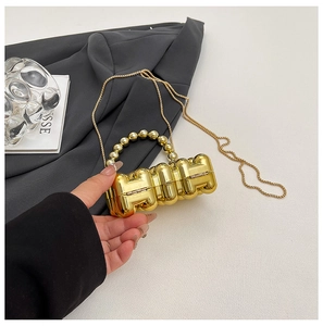 Close-up of golden H-shaped mini evening bag with pearl handle and fine chain strap