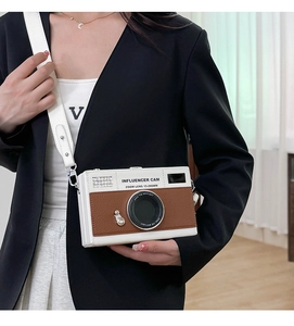 Close-up of camera-shaped crossbody bag featuring color-block leather and wide strap