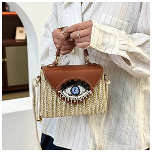 Dettaglio della borsa in paglia con ricamo occhio di Nazar, perle e strass luccicanti