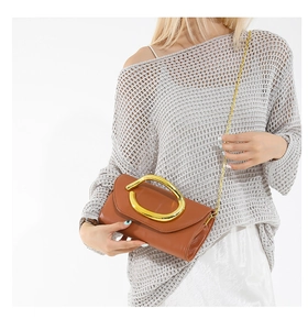 Detail of caramel leather clutch with gold oval handle and fine metal chain strap