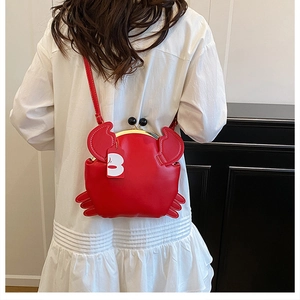 Detail of red crab-shaped crossbody bag with gold metal clasp and 3D claws
