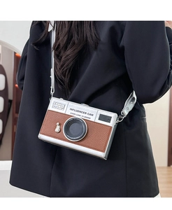Model wearing retro camera-shaped crossbody bag with silver leather strap and color-block design