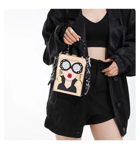 Detail view of pop art handbag with sunglasses graphics and scarf wrapped handle