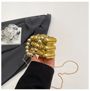 Macro shot of gold metallic mini capsule evening bag with bead handle and chain strap