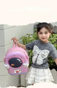 Zaino per bambini con design astronauta rosa tenuto da una bambina su muro di pietra
