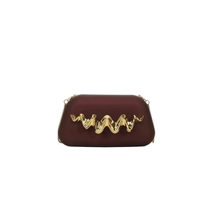 Détail d'un sac de soirée bordeaux avec garniture dorée ondulée et fine bandoulière