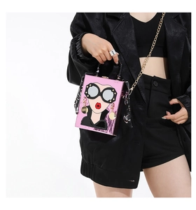 Pink hard-shell crossbody bag with cartoon face and scarf-wrapped handle detail