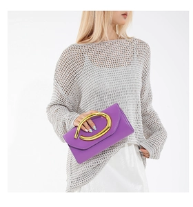 Detail of purple leather envelope clutch bag with unique gold oval metal handle on model