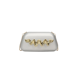 Détail de pochette de soirée avec coque argent mat et ornement en métal doré ondulé