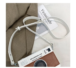 Detail of camera-shaped crossbody bag with white and brown pebbled leather patchwork