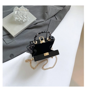 Detail view of the black glossy handbag interior with gold metal clasp and silk scarf handle
