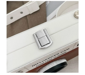 Detail of the camera-shaped crossbody bag featuring a silver metal push-lock and pebble leather