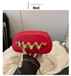 Detail view of red glossy box bag featuring wave-shaped gold buckle and snake chain
