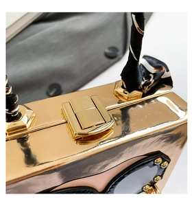Detail of champagne gold box clutch with silk scarf handle and studded sunglasses decor