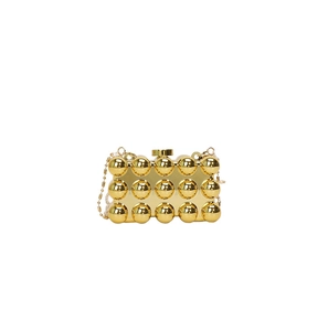 Detail of gold hard-shell evening bag with metallic studs and a delicate bead chain