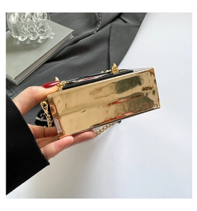 Detailed macro view of black patent leather bag with gold mirror finish and chain strap