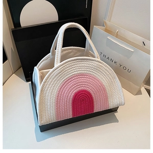 Detail of a white woven cotton rope diaper bag featuring pink rainbow stitch patterns