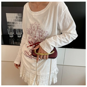Detail of white long sleeve t-shirt with red graphic print and delicate lace skirt