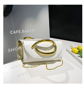 Detail of white leather clutch with gold oval handle and chain strap on marble surface