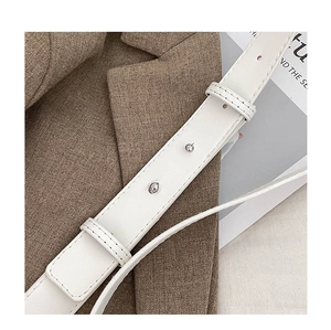 Detail of white leather bag strap with silver ball studs and fine stitching