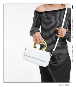 White rectangular flap bag with unique artistic gold handle and shoulder strap