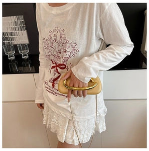 Detail of khaki leather clutch bag with distinctive gold curved metal handle and chain