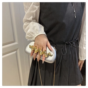 Detail of silver box clutch with unique gold wavy finger ring handle and chain strap
