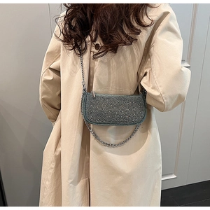 Close-up of sparkling denim chain bag with rhinestones on a beige trench coat