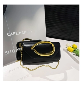 Detail of black leather clutch with luxury gold clasp and detachable chain strap
