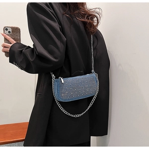 Blue denim baguette bag with silver rivets and chain strap shown on model's shoulder