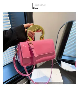 Detail of pink patent leather crossbody bag with artistic gold liquid metal handle