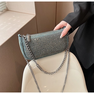 Detail of blue denim shoulder bag featuring sparkling silver rhinestones and metal chain strap