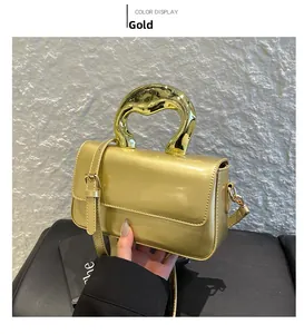 Detail of a shiny gold acrylic handbag with metallic handle and glossy mirror finish