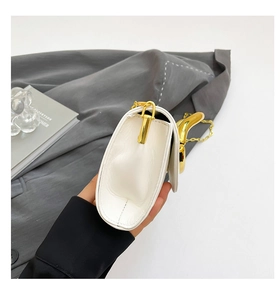 Detail of white faux leather clutch bag with curved gold handle and fine metal chain strap