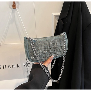 Close-up of blue denim baguette bag with silver rhinestones and chunky metal chain