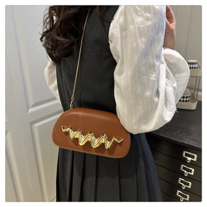 Detail of dark brown shoulder bag with golden wave metal trim and slim chain strap