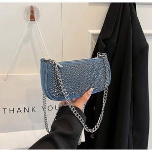 Close-up of denim blue underarm bag with silver studs and chunky metal chain strap
