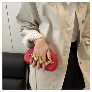Detail view of the red wave pattern evening bag with luxury gold wavy handle and chain strap