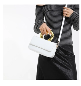 Close-up of a white acrylic small square bag featuring a large gold arc metal handle