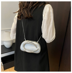 Silver mini acrylic crossbody bag with C-shaped metal frame worn over the shoulder