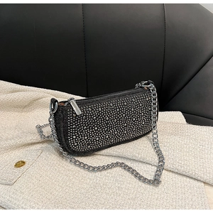 Close-up of sparkling rhinestones on black denim underarm bag with silver chain