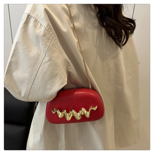 Close-up of a red acrylic evening bag featuring a gold wave handle and a fine chain strap