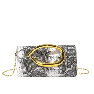 Macro detail of snakeskin pattern leather and gold C-shaped metal clasp on crossbody bag
