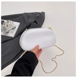 Detail of white acrylic evening bag with gold snake chain and minimalist shell design