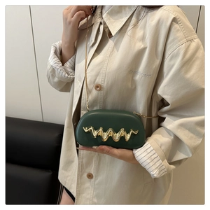 Close-up of dark green leather evening bag with golden wave metal trim and fine chain strap