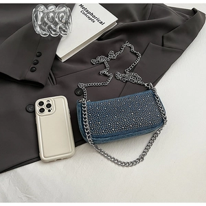 Detail view of denim handbag featuring silver studs and a metallic chain strap