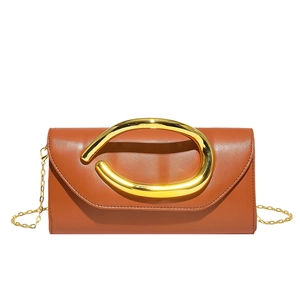 Detail of brown leather envelope clutch with a large gold twisted handle and chain