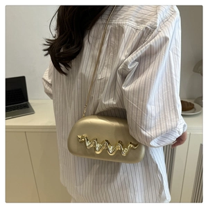 Detailed macro view of champagne gold wave pattern on metallic evening clutch bag